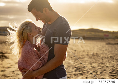 People in love and golden sunset outdoor - man and woman couple hug and look each other with beach in background - concept of protection and life together forever People in love and golden sunset outdoor - man and woman couple hug and look each other with beach in background - concept of protection and life together forever 73257596