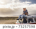Young love couple sit down on a roof van enjoy travel lifestyle and holiday vacation together - concept of van life and free alternative trip with pretty couple enjoying outdoor and hug 73257598