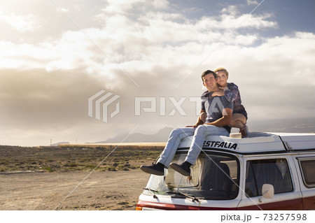 Young love couple sit down on a roof van enjoy travel lifestyle and holiday vacation together - concept of van life and free alternative trip with pretty couple enjoying outdoor and hug Young love couple sit down on a roof van enjoy travel lifestyle and holiday vacation together - concept of van life and free alternative trip with pretty couple enjoying outdoor and hug 73257598