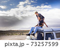 Happy couple enjoy the roof van together having fun in travel holiday alternative vacation - people together in road trip with transport vehicle and love life concept with blue sjy in background and 73257599