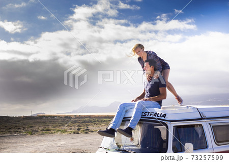 Happy couple enjoy the roof van together having fun in travel holiday alternative vacation - people together in road trip with transport vehicle and love life concept with blue sjy in background and Happy couple enjoy the roof van together having fun in travel holiday alternative vacation - people together in road trip with transport vehicle and love life concept with blue sjy in background and 73257599