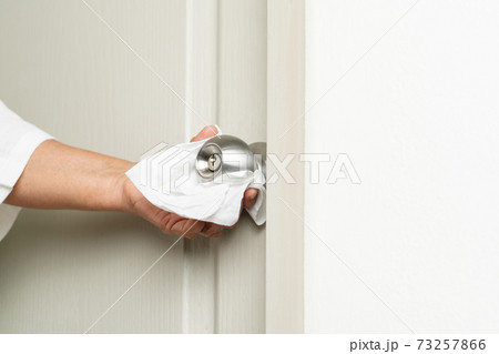 Cleaning door knob with alcohol spray for Covid-19 Coronavirus prevention 73257866