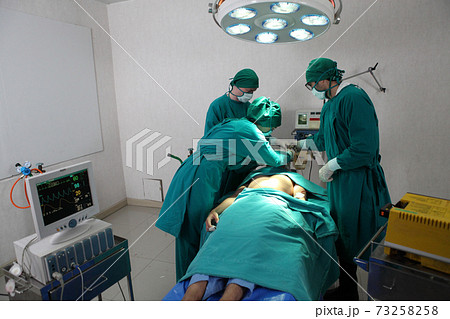 Team of professional surgeons performing operation in hospital , they are holding defibrillator and help while patient will die operation room at hospital Team of professional surgeons performing operation in hospital , they are holding defibrillator and help while patient will die operation room at hospital 73258258