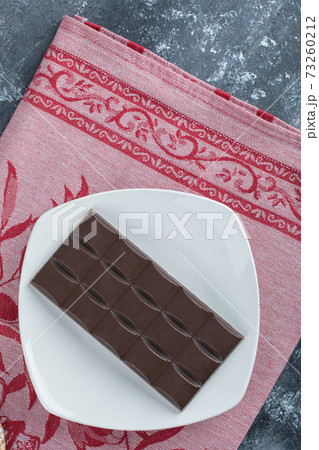 Bar of delicious chocolate on a white plate 73260212