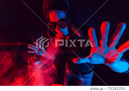 bearded man smokes a hookah and exhales a cloud of smoke bearded man smokes a hookah and exhales a cloud of smoke 73262201