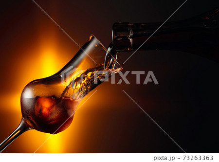 Pouring an alcoholic beverage into a steamed glass with natural ice. Pouring an alcoholic beverage into a steamed glass with natural ice. 73263363