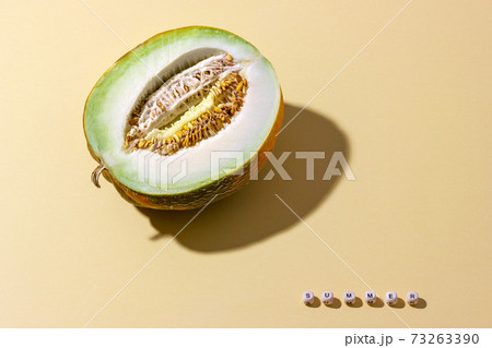 A half of delicious melon with seeds on light beige background. Word summer on small wooden cubes A half of delicious melon with seeds on light beige background. Word summer on small wooden cubes 73263390