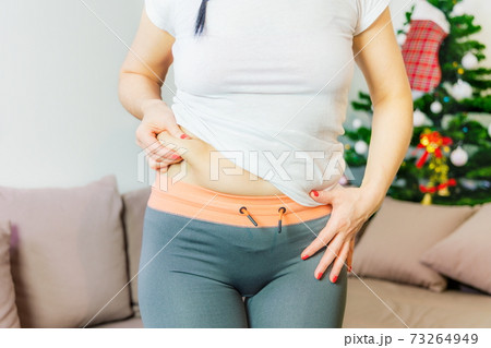Woman showing fat on front side of waist.New Year's weight loss challenge concept Woman showing fat on front side of waist.New Year's weight loss challenge concept 73264949