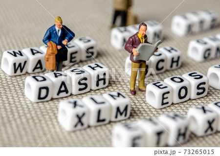 set of popular crypto coins forming rows made of white cubes with black capital letters and miniature businessmen figurines having a team meeting 73265015