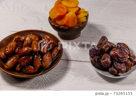 Dried apricots and dates fruit on white wooden table Dried apricots and dates fruit on white wooden table 73265155