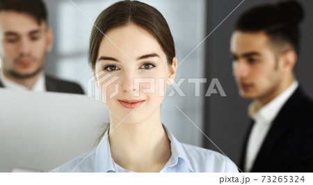 Business woman and group of diverse business people at the background in modern office. Multi ethnic teamwork and business concept Business woman and group of diverse business people at the background in modern office. Multi ethnic teamwork and business concept 73265324