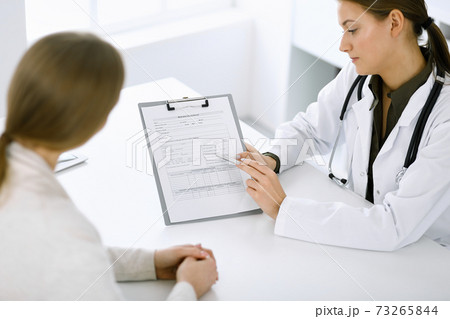 Woman-doctor and patient sitting and talking at hospital office. Green color blouse suits to therapist. Medicine and healthcare concept Woman-doctor and patient sitting and talking at hospital office. Green color blouse suits to therapist. Medicine and healthcare concept 73265844