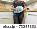 Adult woman wiping plates at kitchen 73265868