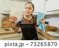 Angry woman smashing plate in kitchen 73265870