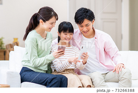 リビングでスマホを見る若い家族 73266388