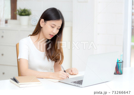 Young asian woman writing on notebook for planning working and using laptop computer on desk. 73266647