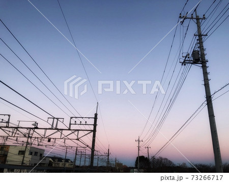 紫とピンクの淡い夕暮れの空と電線の連なる街並みの風景の写真素材