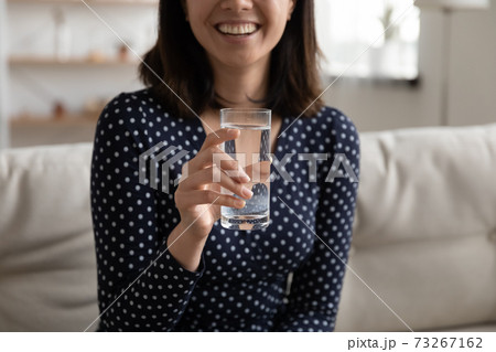 Close up smiling young asian woman holding glass of water. Close up smiling young asian woman holding glass of water. 73267162