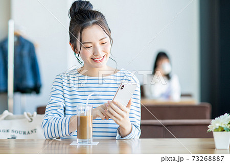 カフェでスマホを見る若い女性 73268887