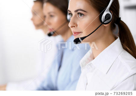 Call center. Group of operators at work. Focus on beautiful business woman in headset 73269205