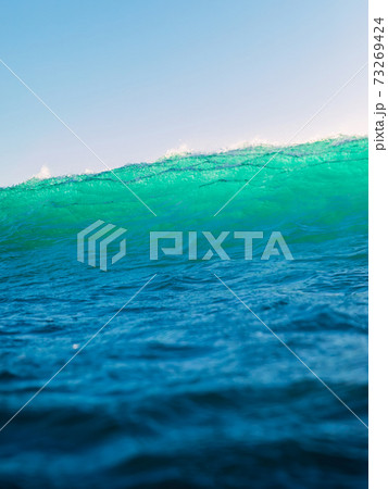 Perfect surfing wave in ocean. Breaking turquoise wave with sun light 73269424