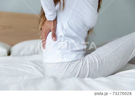Close up exhausted woman touching tensed back muscles after awakening Close up exhausted woman touching tensed back muscles after awakening 73270028