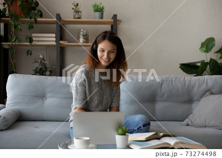 Smiling woman in headphones study online at home 73274498