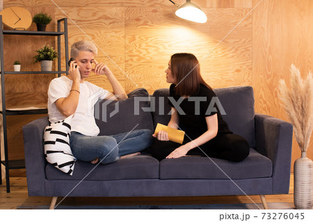Young couple sits on the couch and swears. Girl is very unhappy 73276045