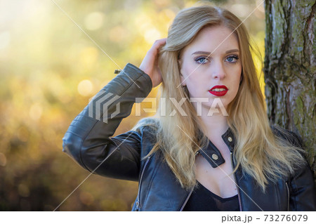 Attractive long hair blond girl with red lips is posing in autumn park. 73276079