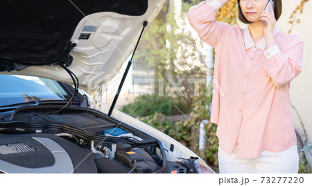 車のトラブルで電話をする若い女性 73277220
