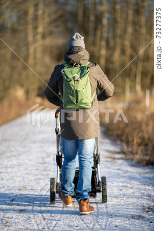 Young modern dad with backpack walking with stroller in the forest Young modern dad with backpack walking with stroller in the forest 73277375