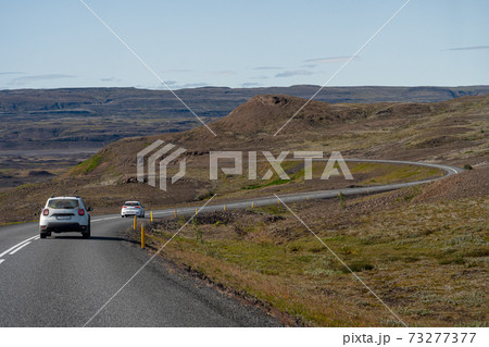 Gravel road with cars and blue sky in southern fjords, Iceland 73277377