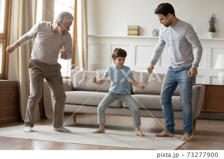Happy three generations of men dance at home 73277900