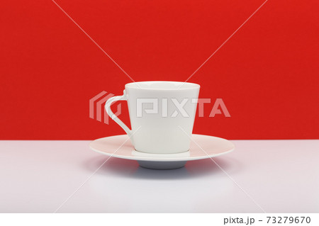 White coffee or tea cup on white table against red background 73279670