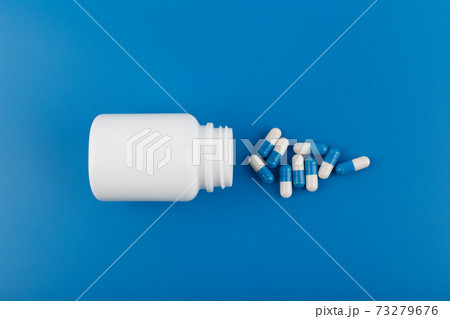 Flat lay with medication bottle and spilled pills on blue background. Concept of medication, vitamins or painkillers Flat lay with medication bottle and spilled pills on blue background. Concept of medication, vitamins or painkillers 73279676