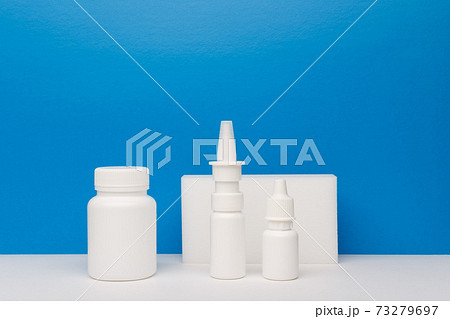 Medication bottle, nose spray and eye drops on white table against blue background with copy space 73279697