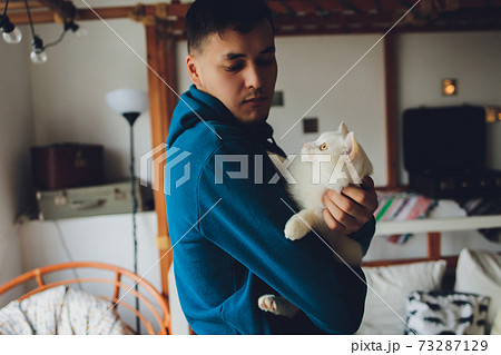 young man holding a white cat close-up. young man holding a white cat close-up. 73287129