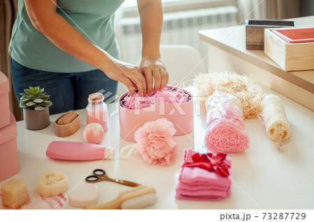 Woman hands holding pink colored heart shaped gift boxes of bath and body products for bridesmaids. 73287729