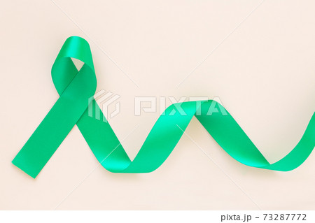Emerald green or jade green ribbon curl on pastel beige background with copy space, symbol for Liver Cancer awareness, World Cancer Day. Healthcare or hospital and insurance concept. Emerald green or jade green ribbon curl on pastel beige background with copy space, symbol for Liver Cancer awareness, World Cancer Day. Healthcare or hospital and insurance concept. 73287772