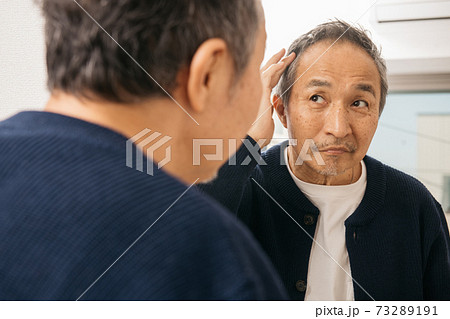 鏡越しにヘアスタイルを見て悩む中高年男性 鏡越しにヘアスタイルを見て悩む中高年男性 73289191