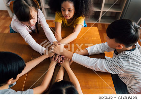 Multiethnic school children with hands touching on top of each other Multiethnic school children with hands touching on top of each other 73289268