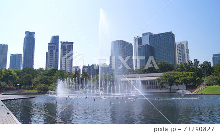 KUALA LUMPUR, MALAYSIA - 13 APRIL 2015: A body of water and a fountain with a city in the background KUALA LUMPUR, MALAYSIA - 13 APRIL 2015: A body of water and a fountain with a city in the background 73290827