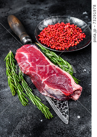 Fresh raw marbled beef meat sirloin steak on a knife. Black background. Top view 73291978