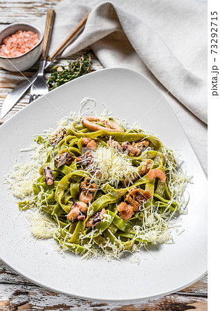 Green Fettuccine spinach pasta with seafood in cream sauce. White background. Top view Green Fettuccine spinach pasta with seafood in cream sauce. White background. Top view 73292715