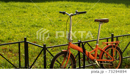 Walking compact city bike on green grass background with copy space. City tourism and bike rental service 73294894