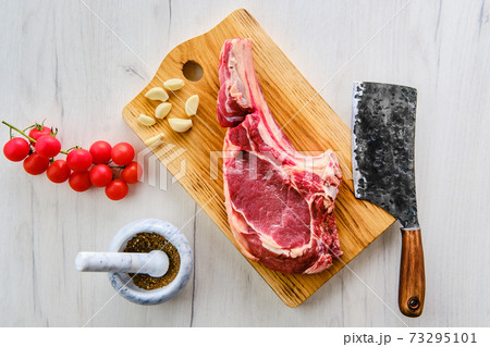 Beef ribeye steak bone-in with spice on wooden cutting board 73295101