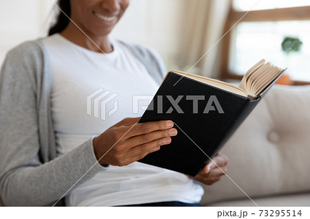 Happy young african ethnicity woman reading favorite book. 73295514