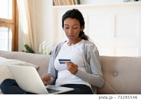 Focused young african american woman shopping online. 73295546