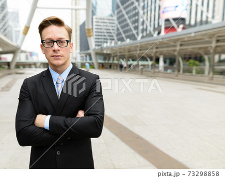 Young handsome blond businessman with arms crossed in the city outdoors 73298858
