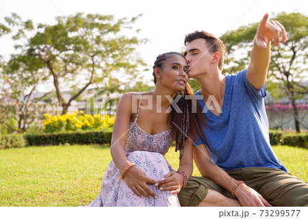 Portrait of young multi ethnic couple relaxing together at the park Portrait of young multi ethnic couple relaxing together at the park 73299577